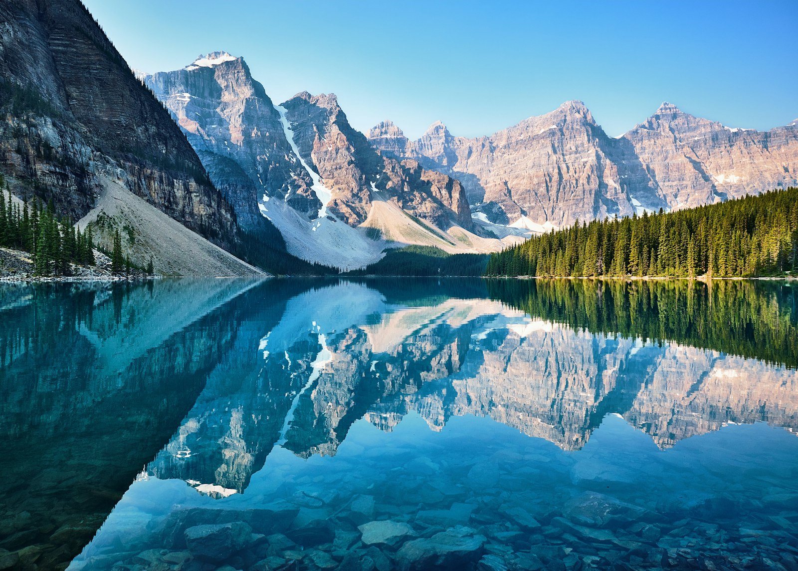 Reflections of snow-capped Canadian Rocky Mountains in a turquoise glacial lake at sunrise