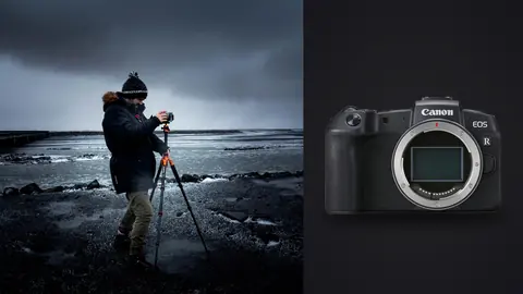 Canon EOS RP product photo beside travel photographer using a tripod-mounted camera on a moody coastal shoreline