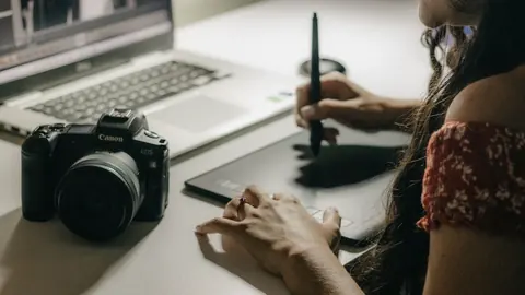 Person editing a photo on a laptop at home with a camera nearby
