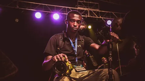 Photographer with media pass and camera in the photo pit under purple stage lights
