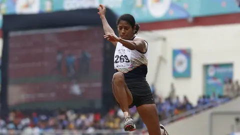 Long jumper at the peak of her flight above the sand pit