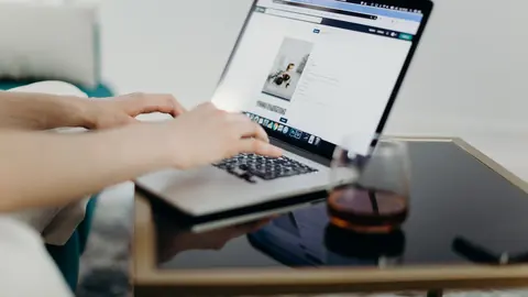 Hands typing on a laptop uploading a photo to a web page