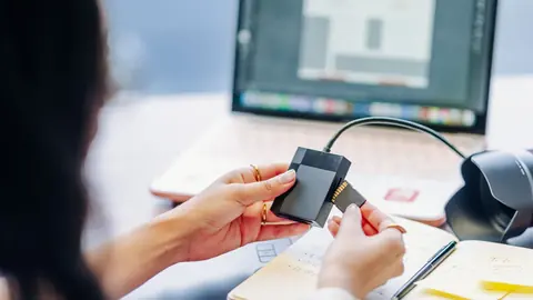 Hand inserting a memory card into a reader connected to a laptop