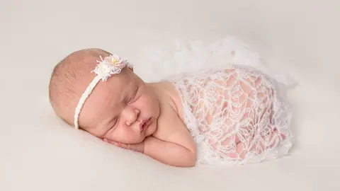 A sleeping newborn wrapped in lace for a studio photography session