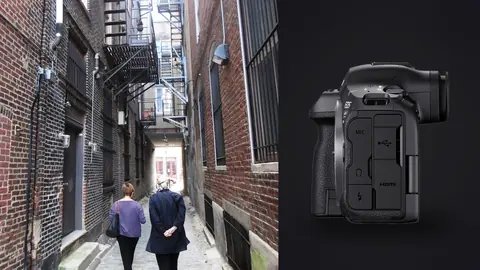 Canon EOS R5 Mark II product photo beside two people walking away down a narrow brick alley