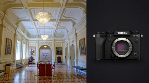 Fujifilm X-T5 product photo beside grand hall with chandeliers, portraits and wood benches
