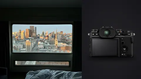 Fujifilm X-T5 product photo beside hotel bed facing large window with city skyline