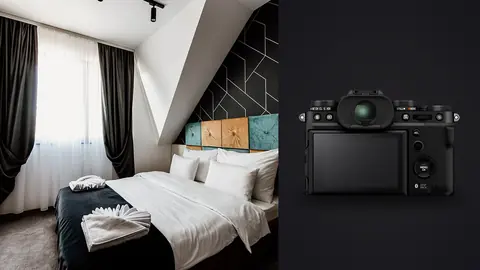Fujifilm X-T5 product photo beside modern hotel bedroom with a neatly made bed and dark curtains