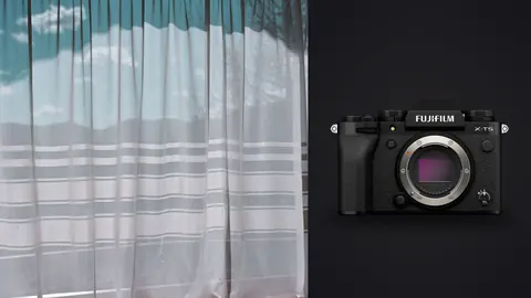 Fujifilm X-T5 product photo beside sheer curtain with sky and clouds visible