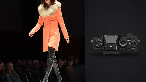Fujifilm X-T5 product photo beside model in a peach coat with fur collar and sunglasses on runway
