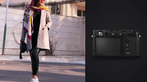Fujifilm X100VI product photo beside woman in a beige coat and colorful scarf walks a city street