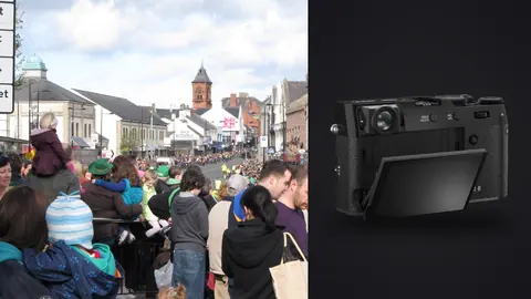 Fujifilm X100VI product photo beside dense crowd watching a parade in a town square