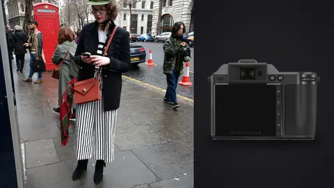 Hasselblad X2D 100C product photo beside woman in a military style jacket and striped trousers on a city street