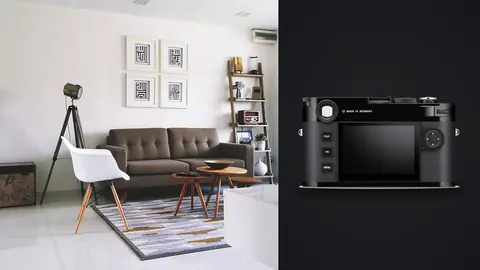 Leica M11 product photo beside monochrome living room with grey sofa and gallery wall
