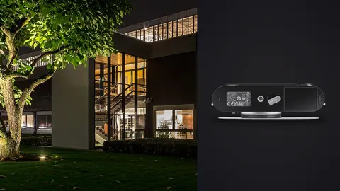 Leica M11 product photo beside modern building exterior with warm lit windows at dusk