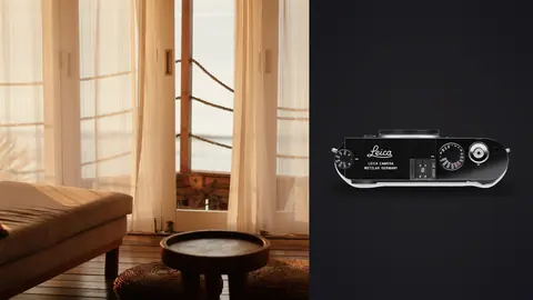 Leica M11 product photo beside leather armchair by curtained window in warm light