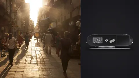 Leica M11 product photo beside people walking a sunlit street market at golden hour