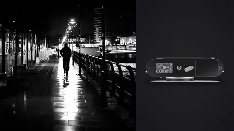 Leica M11 product photo beside lone figure walking a rainy riverside promenade at night