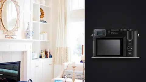 Leica Q3 product photo beside cozy living room with fireplace, mirror and built-in shelving