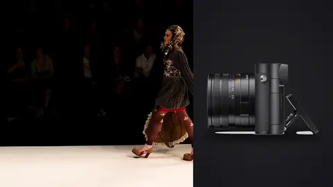 Leica Q3 product photo beside model in a knit dress and floral headscarf walking a dark runway