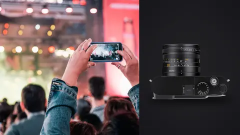 Leica Q3 product photo beside crowd filming concert on phone with stage lights