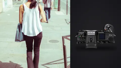 Nikon Z6 III product photo beside woman in a white tank top walks away down a city sidewalk