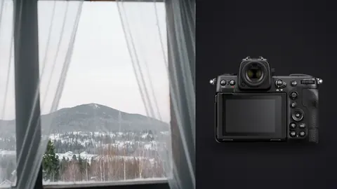 Nikon Z8 product photo beside sheer curtains framing mountain and snow view