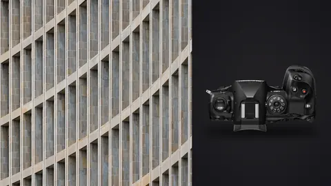 OM System OM-1 Mark II product photo beside curved modern building facade with repeating window pattern