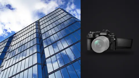 OM System OM-1 Mark II product photo beside glass skyscraper facade reflecting clouds against blue sky