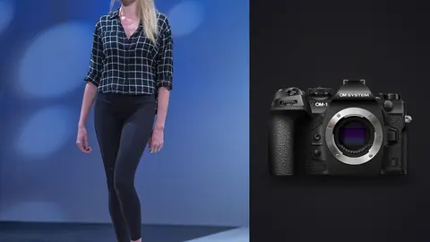 OM System OM-1 Mark II product photo beside model in a plaid shirt and black leggings walking a runway