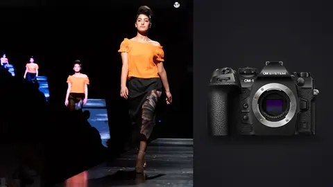OM System OM-1 Mark II product photo beside model in an orange top and dark skirt on a runway
