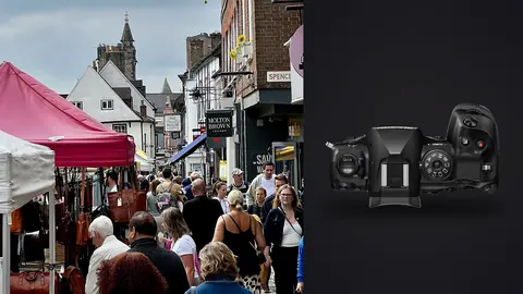 OM System OM-1 Mark II product photo beside crowded shopping street lined with market stalls
