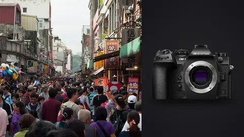 OM System OM-1 Mark II product photo beside crowded old street lined with market shops