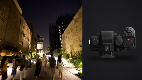 Panasonic Lumix S5IIX product photo beside pedestrians walking an elevated night promenade between buildings