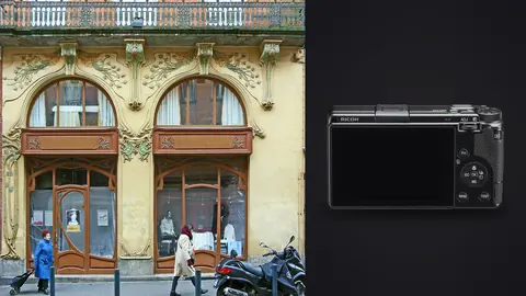 Ricoh GR IIIx product photo beside art nouveau building facade with ornate arched windows