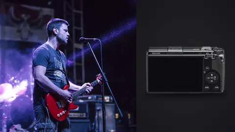 Ricoh GR IIIx product photo beside guitarist performing on stage under purple lights