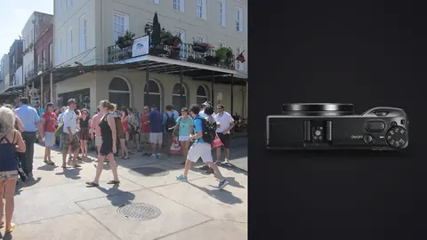Ricoh GR IIIx product photo beside crowd of tourists walking past a balconied corner building