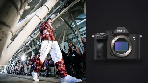 Sony a7 IV product photo beside model in a bold red plaid jacket and wide trousers on runway