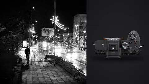 Sony a7 IV product photo beside lone figure on a wet night street with string lights