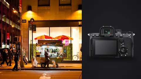 Sony a7 IV product photo beside hot dog vendor at a street cart with pedestrians walking by at night