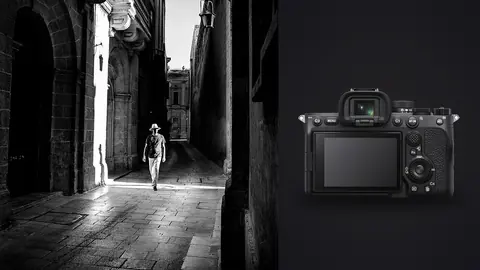 Sony a7 IV product photo beside man in a hat walking down a sunlit stone alley