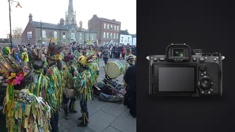 Sony a7 IV product photo beside crowd of costumed folk performers in a market square