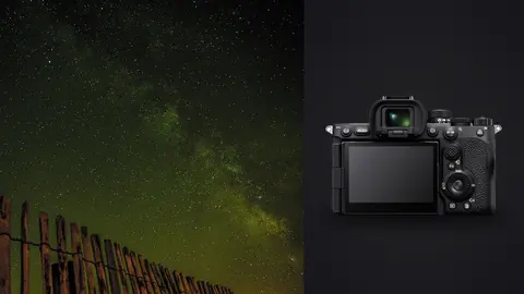 Sony a7R V product photo beside green-tinted milky way glowing beyond a wooden fence line