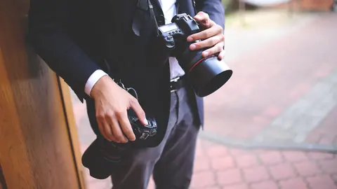 Wedding photographer in a suit carrying two camera bodies