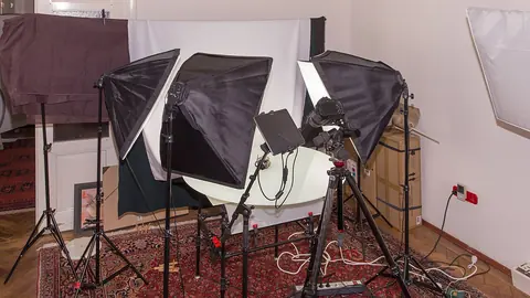 Small home studio with three softbox lights around a white seamless product turntable