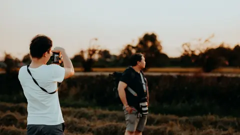 Photographer photographing another photographer carrying camera gear outdoors