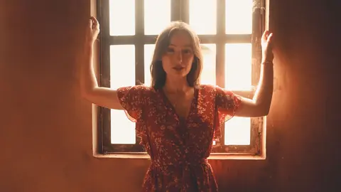 Woman backlit at a bright window with blown out panes